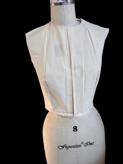 Calico bodice block fitted on a dress form, viewed from the front, with the seam lines pinned.