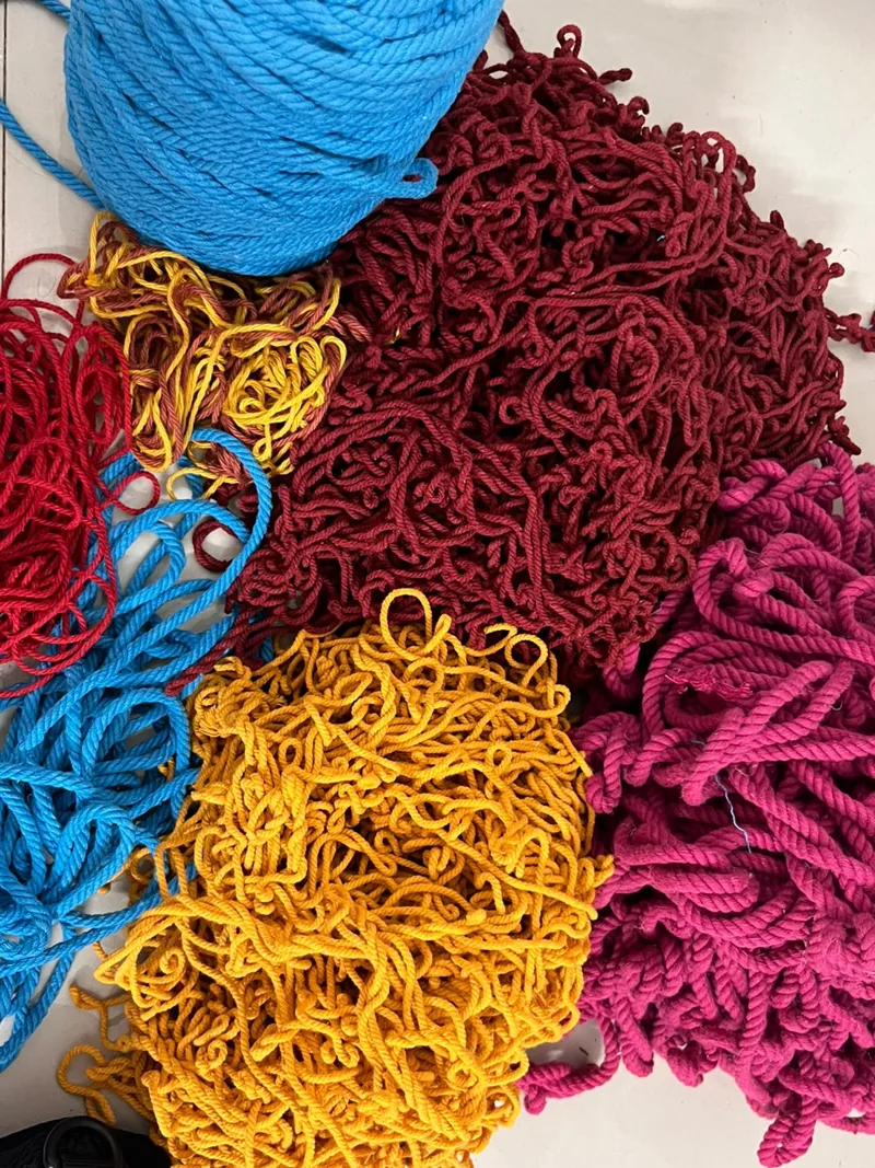 A pile of unravelled yarn in bright blue, crimson, mustard yellow and magenta.